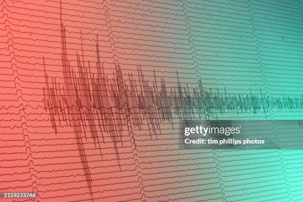 a seismograph recording and indicating the volatile activity of an earthquake, volcanic eruption or explosion with high and low seismic waves forms above and below the neutral axis. - terremoto fotografías e imágenes de stock