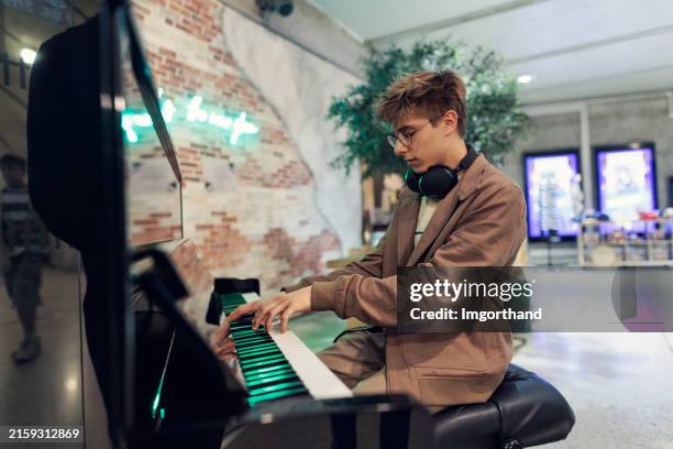 teenage boy playing piano at the monaco train station. - pianist stock pictures, royalty-free photos & images