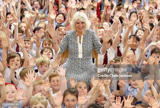 Queen Camilla, pupils and teachers raise their hands in celebration of the Christ Church C of E Primary School's Literary Festival on June 26, 2024...
