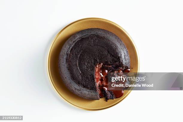 a delicious chocolate lava cake with a molten center on a golden plate - chocolate lava stock pictures, royalty-free photos & images