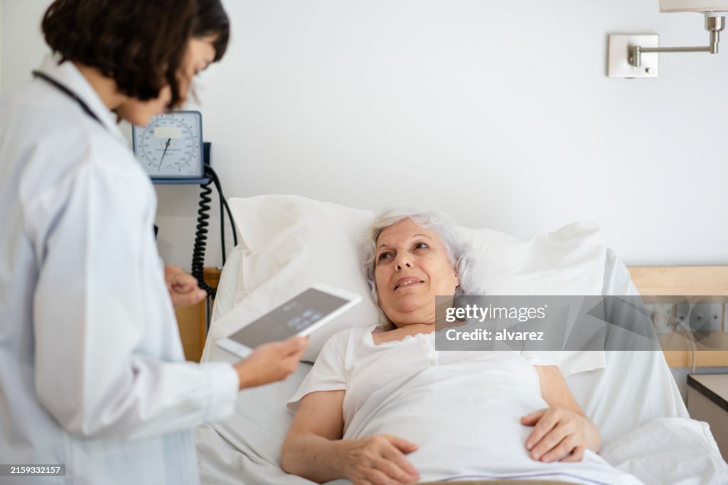 Un médecin donne des instructions détaillées sur les médicaments à une femme âgée dans un lit d’hôpital