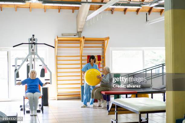 elderly patients exercising with therapist at rehabilitation center - exercise machine stock pictures, royalty-free photos & images