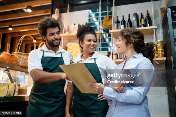 grocery store manager reviewing inventory with workers in delicatessen - allied stores stock pictures, royalty-free photos & images
