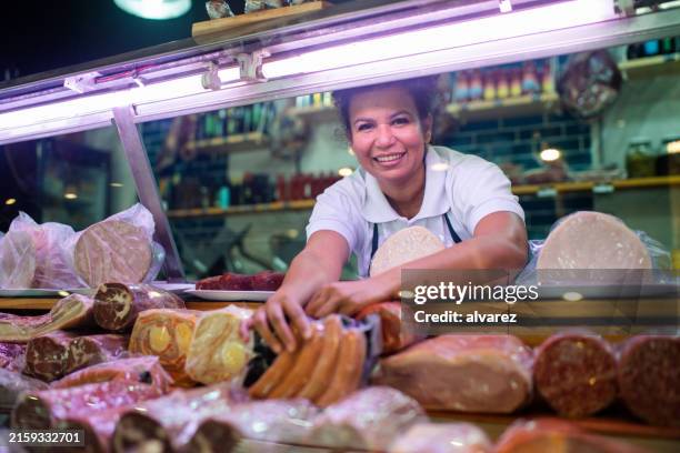 woman arranging the cheese refrigerator display at a delicatessen - grocer stock pictures, royalty-free photos & images