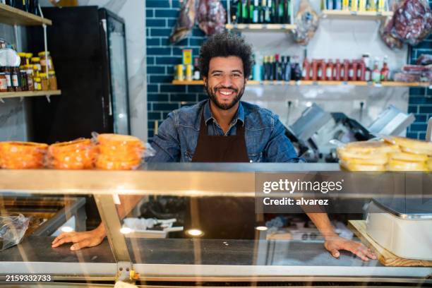 portrait of happy grocery store salesman standing behind the display counter - grocer stock pictures, royalty-free photos & images