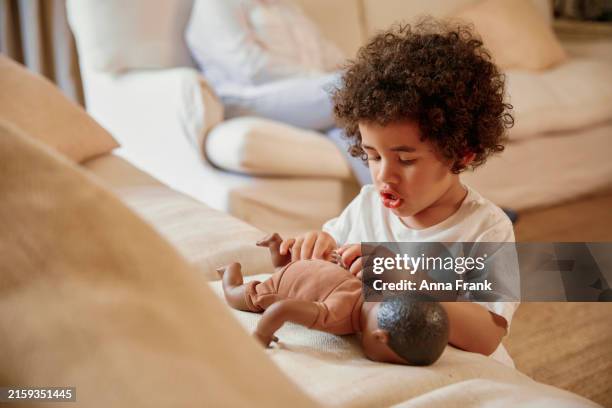 a young boy plays with a doll - black doll stock-fotos und bilder