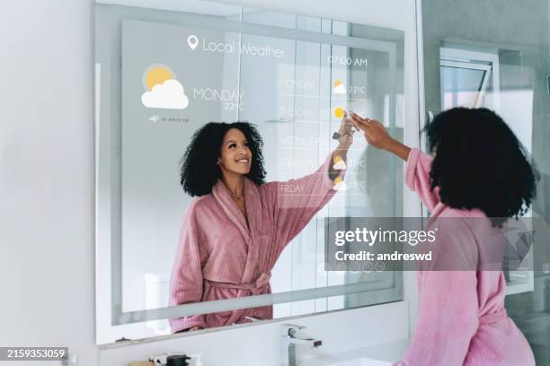 artificial intelligence woman checking weather forecast on smart mirror in bathroom ai - weather forecaster stock pictures, royalty-free photos & images