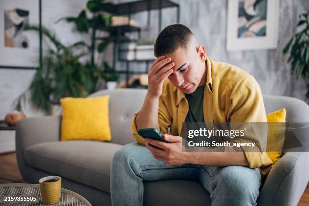 uomo stressato con smartphone e tazza di caffè - solo un uomo giovane foto e immagini stock