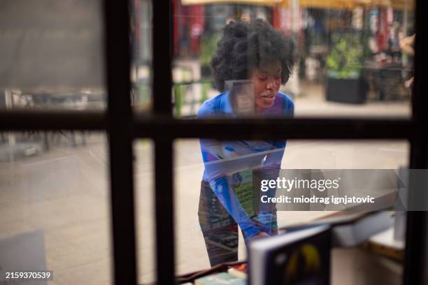 woman looking in bookstore window - etalage stockfoto's en -beelden