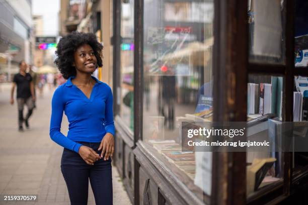 woman looking in bookstore window - book store exterior stock pictures, royalty-free photos & images
