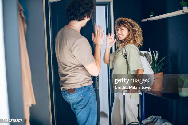 young couple standing in the hallway saying goodbye and leaving - welcome back phrase imagens e fotografias de stock