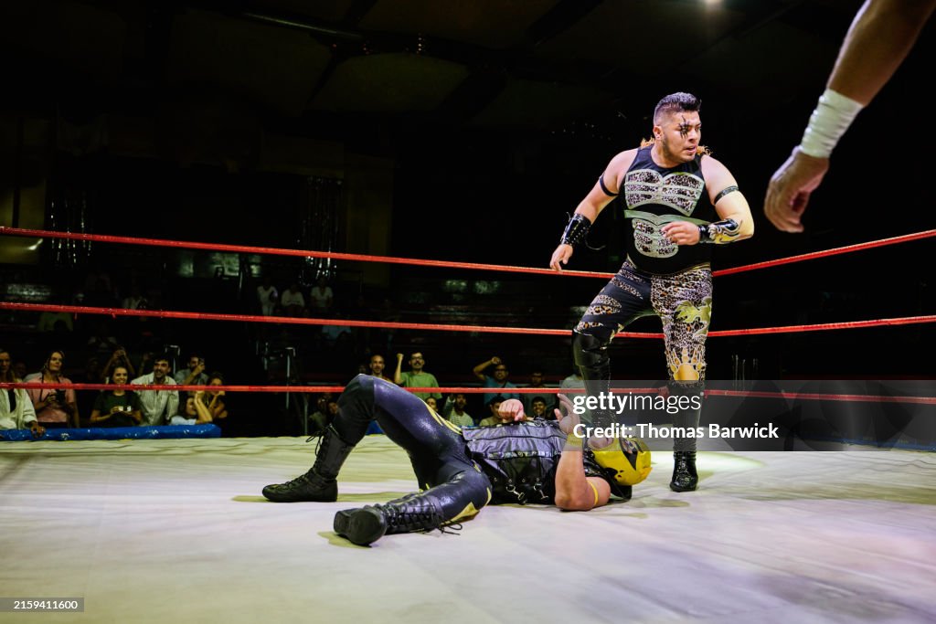 Wide shot luchador with opponent on mat during lucha libre match