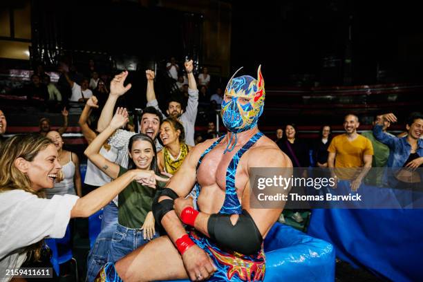 medium wide shot luchador posing with cheering fans in stadium - masculinity stock pictures, royalty-free photos & images