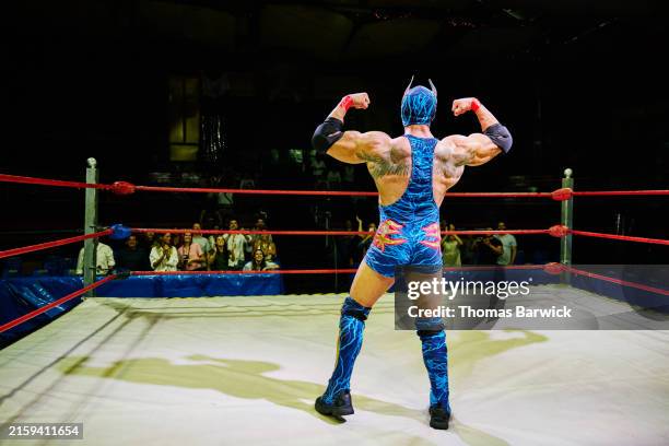 wide shot luchador flexing in front of crowd after winning match - wrestling tattoo stock pictures, royalty-free photos & images