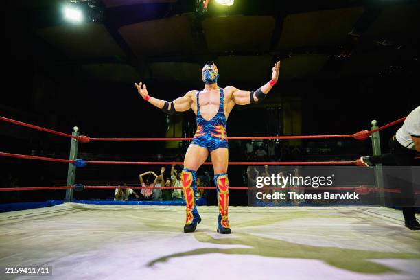 wide shot luchador celebrating in front of crowd after winning match - wrestling stock pictures, royalty-free photos & images
