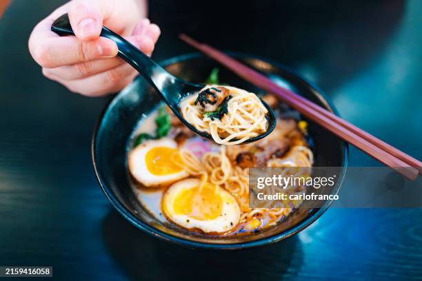 ramen soup in restaurant - holding spoon full of noodles - ramen noodles stock pictures, royalty-free photos & images