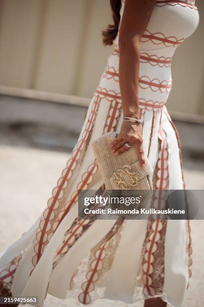 Guest wears long white dress with orange details and beige bag outside Elie Saab show during the Haute Couture Fall/Winter 2024/2025 as part of Paris...