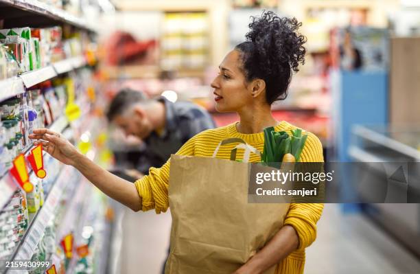 mature hispanic woman shopping in grocery store - paper bag stock pictures, royalty-free photos & images