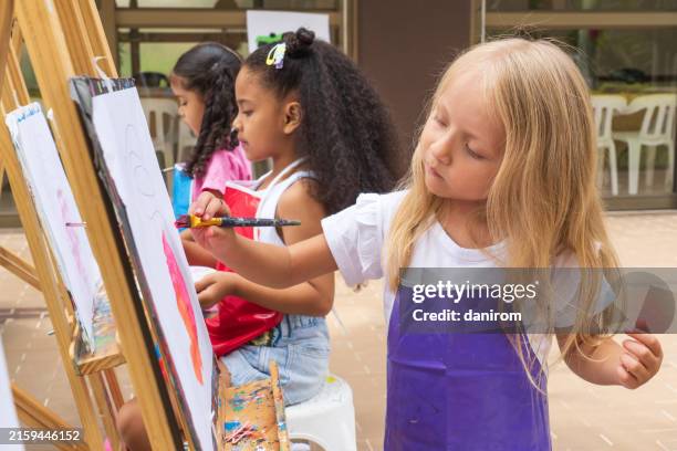 three girls painting together in art class on a sunny day outdoors. - endast flickor bildbanksfoton och bilder
