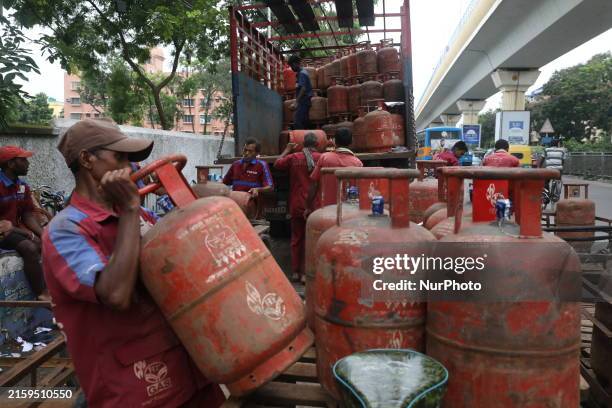 Worker is loading a Liquefied Petroleum Gas cylinder onto his cycle-rickshaw on a road after unloading it from a supply truck in Kolkata, India, on...
