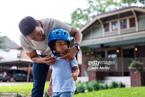 close-up of a caring father putting on safety gear on for his son - protective sportswear stock pictures, royalty-free photos & images