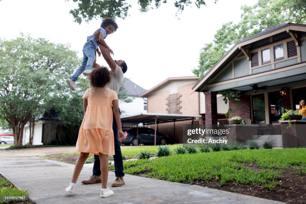 Proud father playing with his kids in front of the house