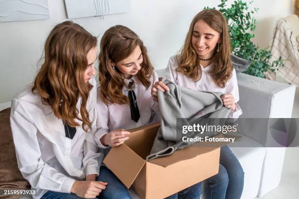 three teenage girls unboxing package inside a home - triplet girls photos et images de collection
