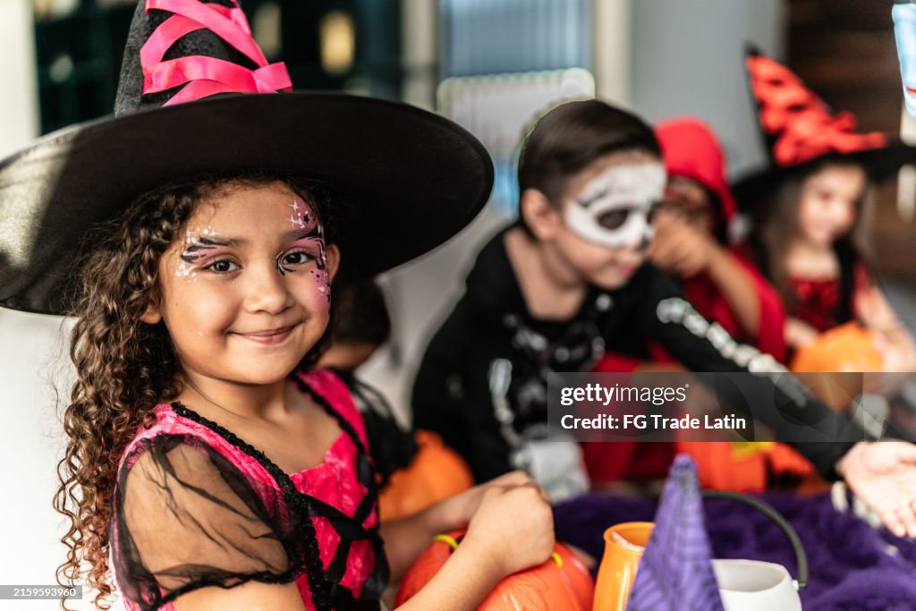 Portrait of a child girl with friends using Halloween costume at home