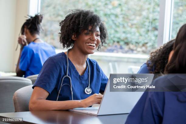 engaged in the classroom setting, a student dressed in scrubs employs her laptop as a dynamic tool for active learning, skillfully documenting important concepts and contributing thoughtfully to the collective discourse. - physiology stock pictures, royalty-free photos & images