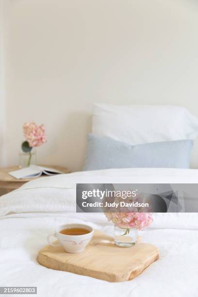 bed with cup of tea and book - nachttisch stock-fotos und bilder