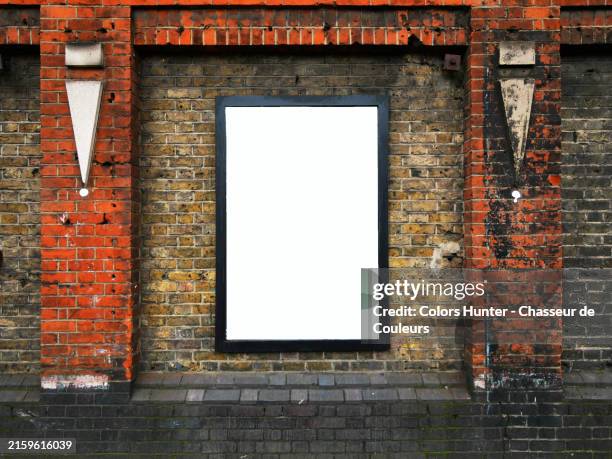 weathered and dirty brick wall, yellow, brown and black with moldings and an empty advertising sign (white background) in london, england, united kingdom. sunlight. natural colors. - urban poster wall stock pictures, royalty-free photos & images