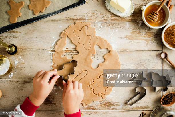 chils coupant de la pâte pour faire des biscuits de noël sur le comptoir de la cuisine - faire cuire au four photos et images de collection