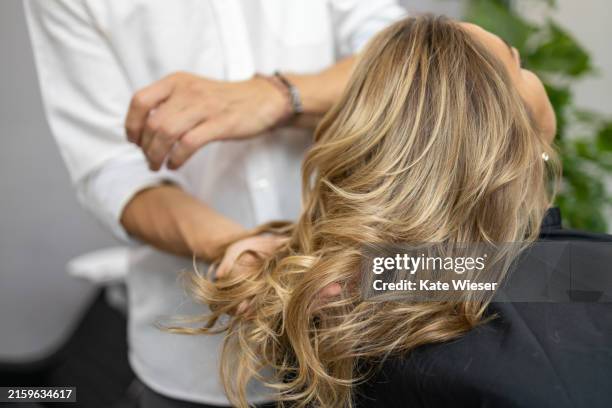 cropped image of a male hairdresser holding customer hair in salon. - blonde beauty hair stock pictures, royalty-free photos & images