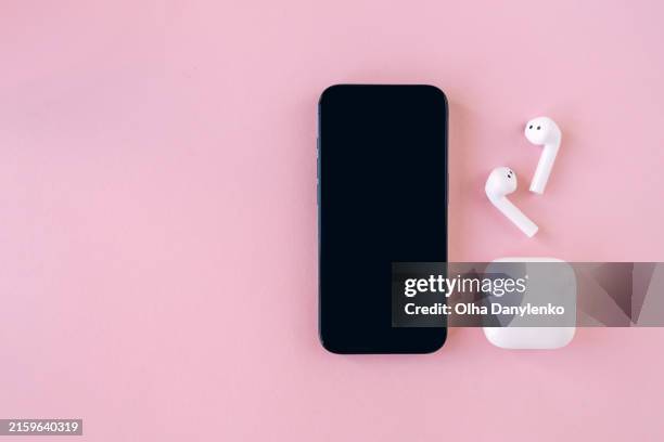 smartphone with headphones on pink background with space for text - wireless headphones stock pictures, royalty-free photos & images