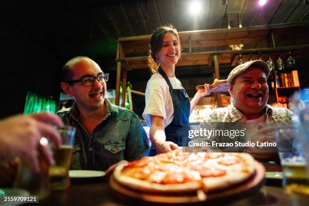 junge kellnerin, die kunden in der pizzeria pizzen serviert - servierplatte stock-fotos und bilder
