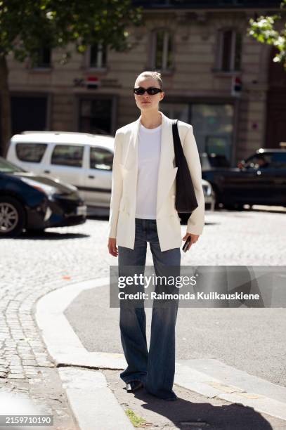 Guest wears a jeans, white top and white blazer outside Schiaparelli during the Haute Couture Fall/Winter 2024/2025 as part of Paris Fashion Week on...