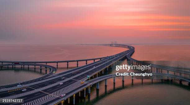 drone point view of jiaozhou bay bridge at the colorful sunset, qingdao city, shandong province, china - armação de construção - fotografias e filmes do acervo
