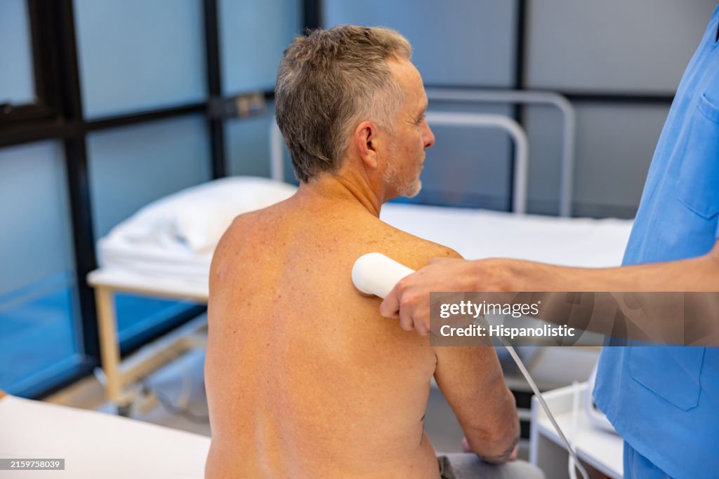 Man in physical therapy getting ultrasound stimulation on his scapula