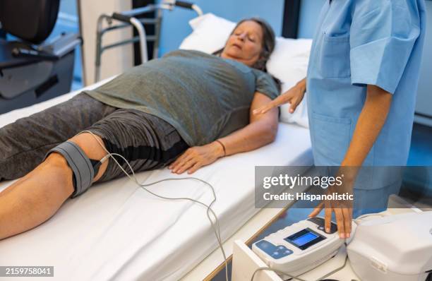 woman in physical therapy getting electrical stimulation on her knee - neuropathy stock pictures, royalty-free photos & images