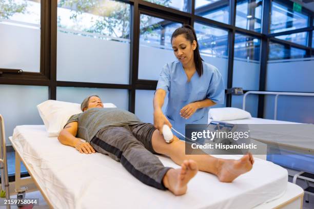 woman in physical therapy getting ultrasound stimulation on her knee - neuropathy stock pictures, royalty-free photos & images