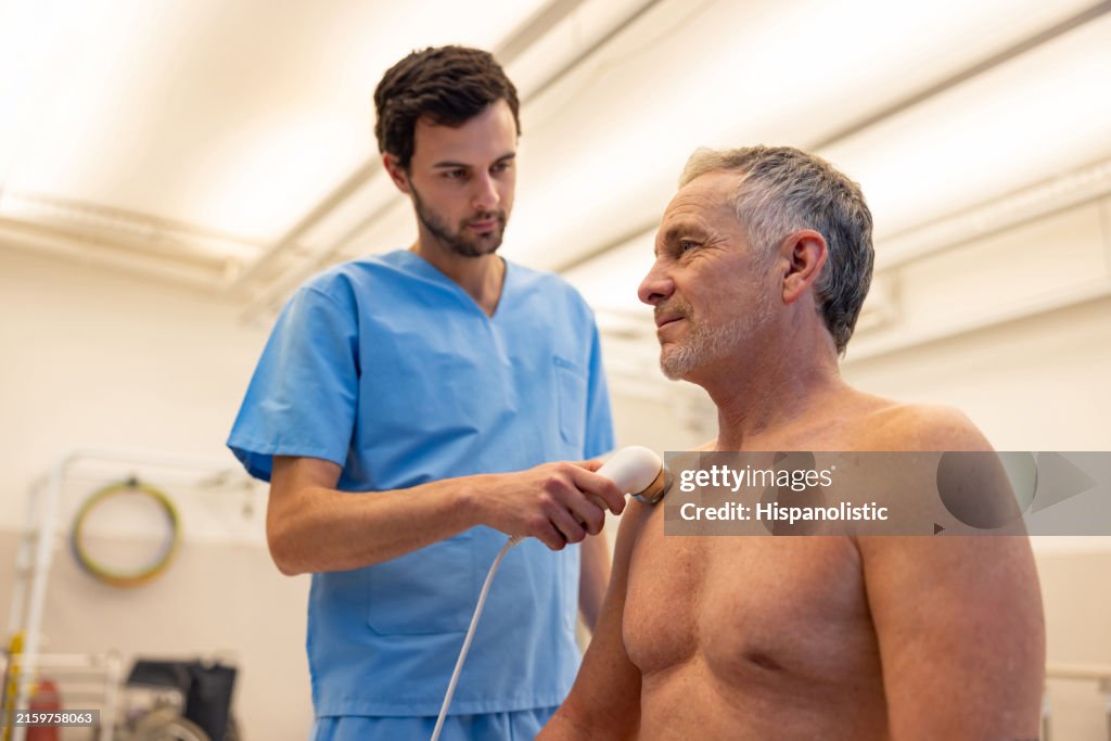 Mann bekommt Ultraschallstimulation an der Schulter in der Physiotherapie