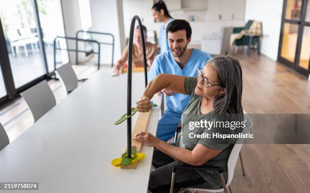 woman moving pieces through a tube with the help of her occupational therapist - terapia ocupacional imagens e fotografias de stock