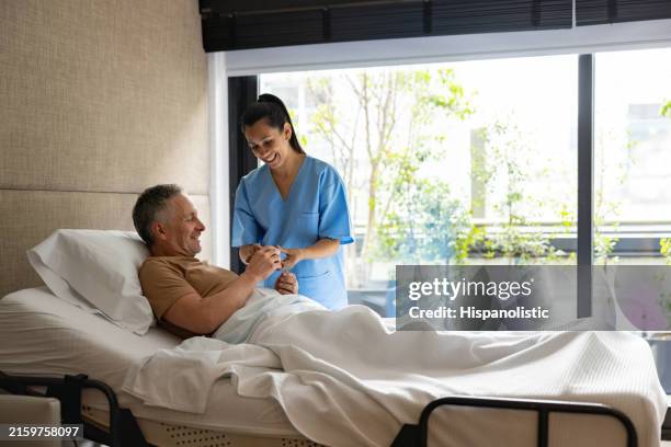 glückliche krankenschwester, die einem patienten erklärt, wie man einen notfallknopf benutzt - krankenstation stock-fotos und bilder
