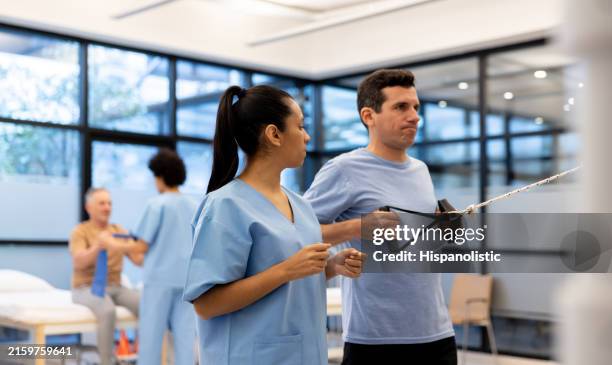 physical therapist guiding a man exercising at a rehabilitation center - neuropathy stock pictures, royalty-free photos & images