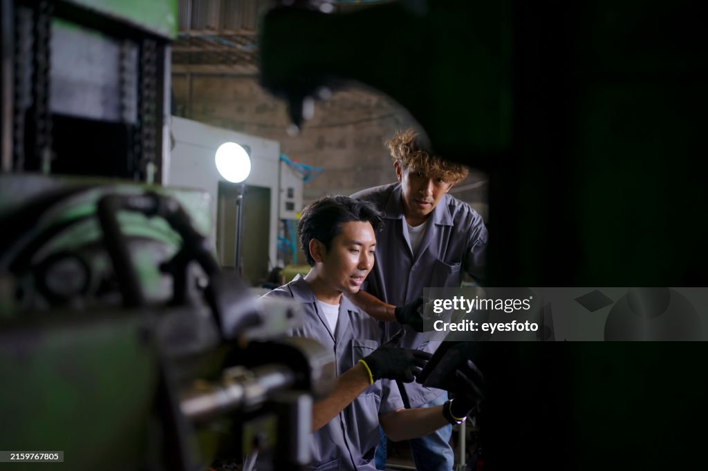 Blue collar workers are working at metal work factory.