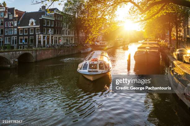 tour boat and sunlight in amsterdam, netherlands - imbarcazione per passeggeri foto e immagini stock