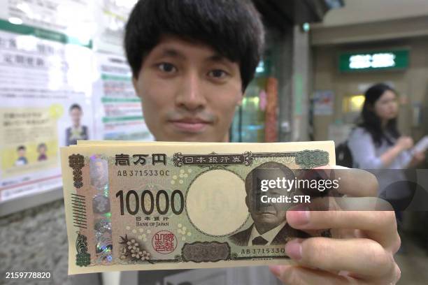 Man holds a new 10,000 yen note at a bank in Saitama on the day the new banknotes were issued on July 3, 2024. / Japan OUT