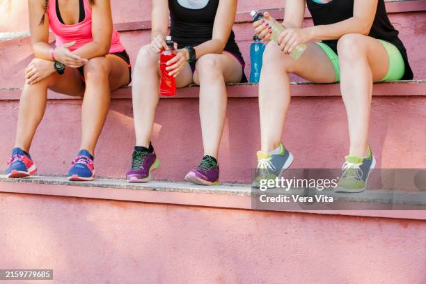 cropped view of fitness women resting after workout in the stadium - energydrink stock-fotos und bilder