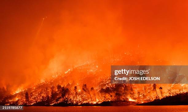 Helicopter shines a light over the Thompson fire as it burns around Lake Oroville in Oroville, California on July 2, 2024. A heatwave is sending...
