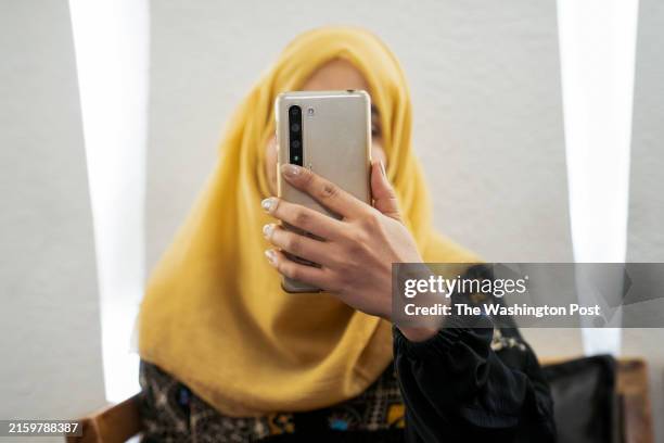 Sajia, whose classmates dropped out over concerns of a crackdown on education, poses for a portrait with her face obscured by her phone to protect...